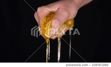 Woman hand squeezes honeycombs full of honey. Dripping,pouring tasty sweet fluid 108561000