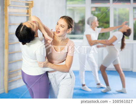 Girl paired up with woman to perform effective impact on pain points while learning self-defense. 108561027