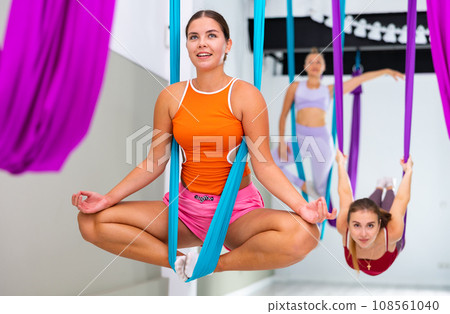 Young woman performing antigravity yoga exercise in gym 108561040