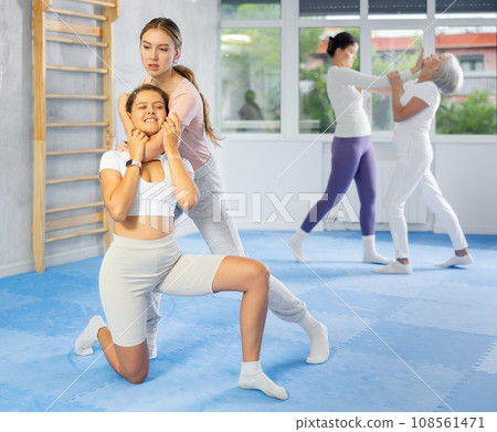 Woman and girl in gym perform basic elements of krav maga self-defense system. Woman and girl in gym perform basic elements of krav maga self-defense system. 108561471