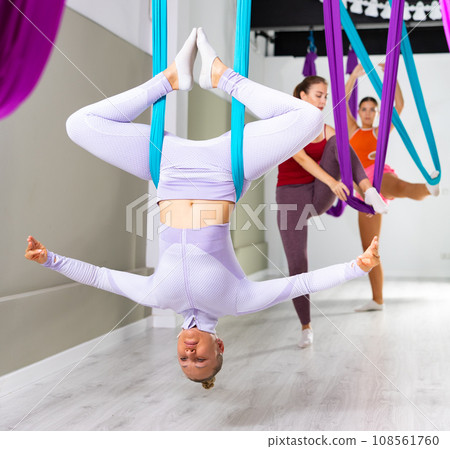 Woman doing inverted bound angle pose in hanging hammock with fingers in mudra Woman doing inverted bound angle pose in hanging hammock with fingers in mudra 108561760