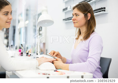 Female nail technician doing manicure to young girl 108561929