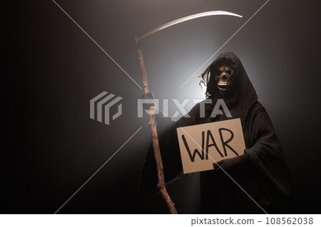 The Grim Reaper holds a poster with the inscription war. Skeleton, skull, silhouette of a man in a The Grim Reaper holds a poster with the inscription war. Skeleton, skull, silhouette of a man in a 108562038
