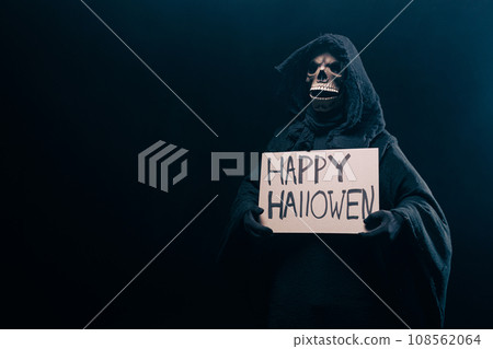 The scary grim reaper is holding a sign happy halloween poster . Death with poster. Skeleton, skull The scary grim reaper is holding a sign happy halloween poster . Death with poster. Skeleton, skull 108562064