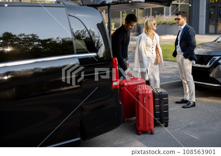 Business couple near minivan taxi with a suitcases and chauffeur 108563901