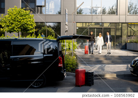 Driver helps a business couple carry their suitcases to the office or hotel Driver helps a business couple carry their suitcases to the office or hotel 108563902