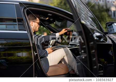Businessman with laptop in car Businessman with laptop in car 108563927