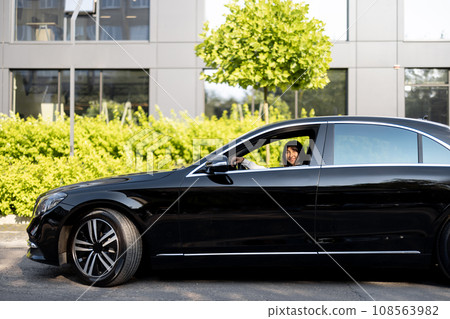 Luxury black car on a street in front of a modern building Luxury black car on a street in front of a modern building 108563982