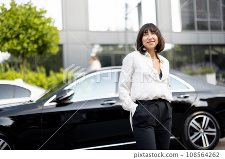 Portrait of business woman in front of a luxury car outdoors Portrait of business woman in front of a luxury car outdoors 108564262