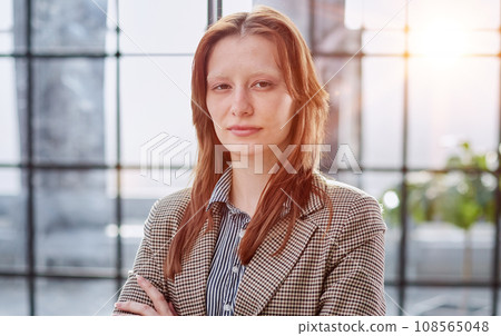 Portrait of a confident young businesswoman standing with her arms crossed in an office. Portrait of a confident young businesswoman standing with her arms crossed in an office. 108565048