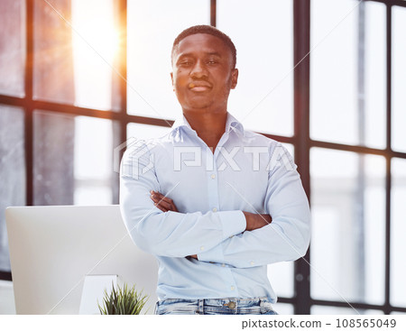 african american man sitting on desk and posing with folded hands african american man sitting on desk and posing with folded hands 108565049