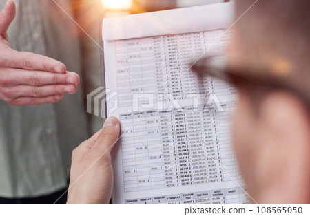 male accounting manager reviewing financial report, sitting at table alone at office 108565050