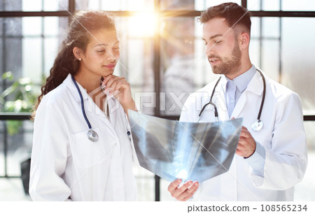 Two busy doctors working with papers and xray images Two busy doctors working with papers and xray images 108565234