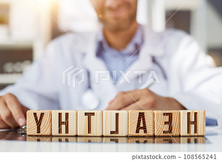 the doctor folded the word healthy from wooden cubes on the table in the hospital 108565241