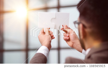 Businessman trying to connect puzzle pieces closeup 108565915