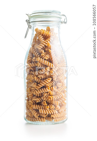 Raw whole grain fusilli pasta. Uncooked pasta in jar isolated on white background. Raw whole grain fusilli pasta. Uncooked pasta in jar isolated on white background. 108566057