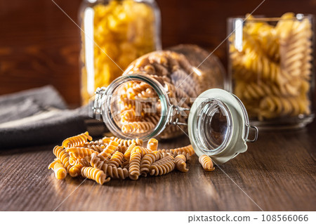 Raw whole grain fusilli pasta. Uncooked pasta on wooden table. Raw whole grain fusilli pasta. Uncooked pasta on wooden table. 108566066
