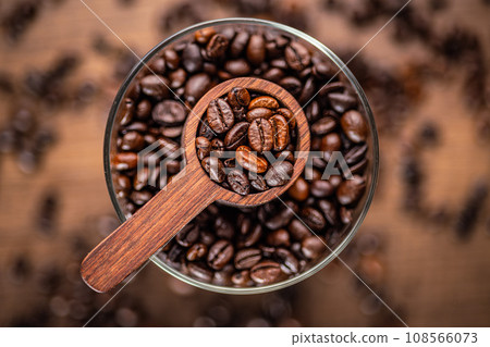 Roasted coffee beans in wooden scoop on wooden table. Top view. Roasted coffee beans in wooden scoop on wooden table. Top view. 108566073
