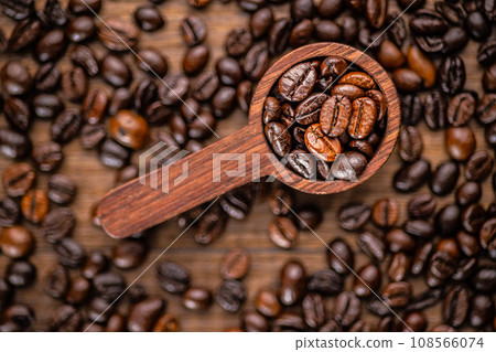 Roasted coffee beans in wooden scoop on wooden table. Top view. Roasted coffee beans in wooden scoop on wooden table. Top view. 108566074