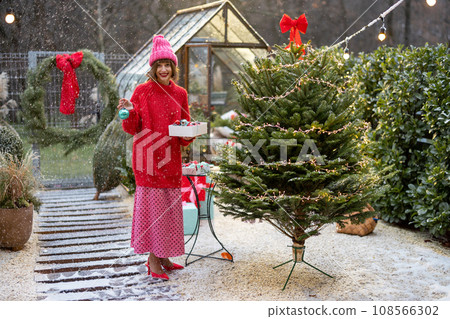 Woman decorates Christmas tree at bacyard Woman decorates Christmas tree at bacyard 108566302