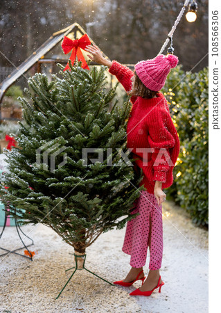 Woman decorates Christmas tree at bacyard Woman decorates Christmas tree at bacyard 108566306