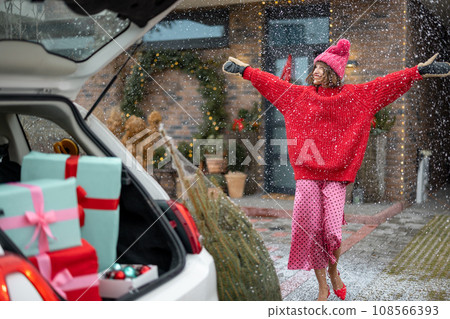 Gift boxes in vehicle trunk in front of a house decorated for winter holidays Gift boxes in vehicle trunk in front of a house decorated for winter holidays 108566393