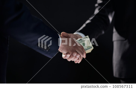 Handshake with the transfer of money on a black background Handshake with the transfer of money on a black background 108567311
