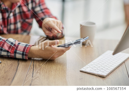 a businessman in the office uses a phone, looks at the screen of a smartphone, browses the Internet 108567354