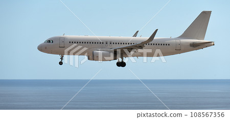 The plane lands over the ocean.Airplane, passengers flying in the sky, preparing to land at the airport 108567356