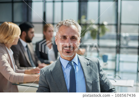 male boss against the background of her colleagues looks at the camera in a modern office 108567436