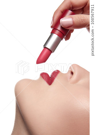 Close up view of model applying red lipstick. Professional fashion vivid make-up. Matte lipstick on full lips. Concept of style. Close up view of model applying red lipstick. Professional fashion vivid make-up. Matte lipstick on full lips. Concept of style. 108567911