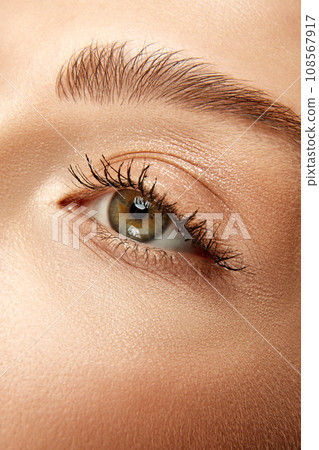 Cropped. Extreme close up view photo of woman with well-kept skin and natural fashion make-up. Eyes, lashes and brows. 108567917