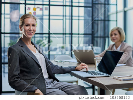 Young woman with computers at desk in office Young woman with computers at desk in office 108568133