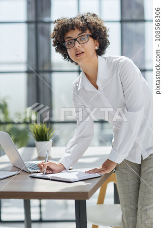 business woman writing at her desk in a modern office 108568306
