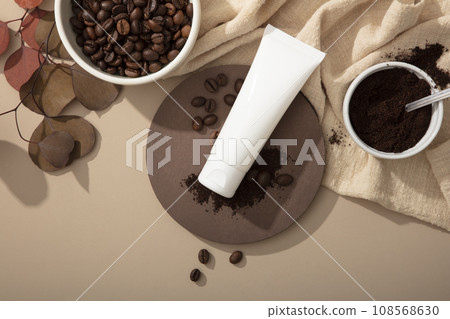 Mockup scene for advertising cosmetic with coffee ingredient. An empty white tube displayed on brown background with coffee beans, coffee powder and beige cloth. Top view 108568630