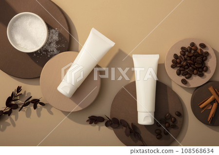 Mockup bottle of cosmetic displayed on round podiums with coffee beans, bath salt and cinnamon sticks on brown background. Top view, concept for advertising organic cosmetics 108568634