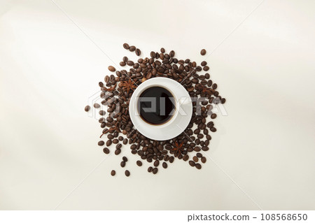 Top view of ceramic cup of coffee placed on brown roasted coffee beans on white background. Clean coffee is an effective active ingredient that helps reduce depression of the nervous system Top view of ceramic cup of coffee placed on brown roasted coffee beans on white background. Clean coffee is an effective active ingredient that helps reduce depression of the nervous system 108568650