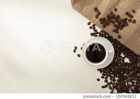 On the white background, a cup of coffee displayed with coffee beans and brown burlap. Blank space for design, presentation product with ingredient from coffee. Top view 108568651