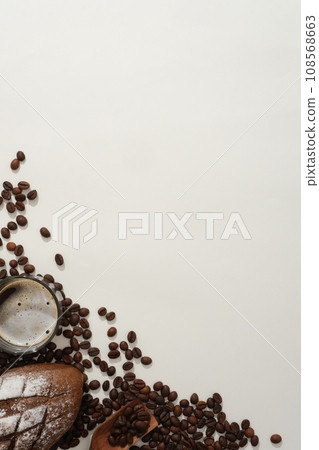 Creative background for advertising with blank space for design make from coffee beans. On a white background, cup of coffee, bread and coffee beans decorated on lower left corner. Top view  108568663