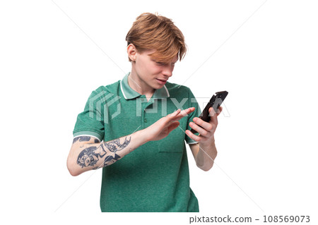 young european man with red hair carefully reads messages on the phone 108569073