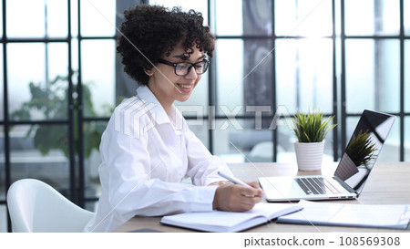 Portrait of Young Successful Caucasian Businesswoman Sitting at Desk Working on Laptop Portrait of Young Successful Caucasian Businesswoman Sitting at Desk Working on Laptop 108569308