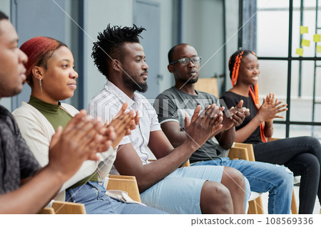 Group of men and women sit in a row and applaud a man who puts forward an idea or says something. Group of men and women sit in a row and applaud a man who puts forward an idea or says something. 108569336