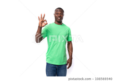 A 30-year-old African man dressed in a light green t-shirt points his hand at an advertisement A 30-year-old African man dressed in a light green t-shirt points his hand at an advertisement 108569340