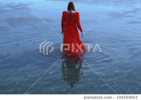 Back view of woman in a red dress walking in water. Generative AI 108569603