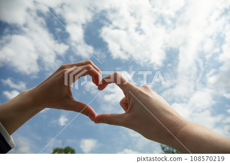 Heart, female hands and sky, close up 108570219