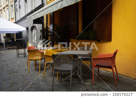 Yellow wall, chairs and tables in outdoor cafe Yellow wall, chairs and tables in outdoor cafe 108570227