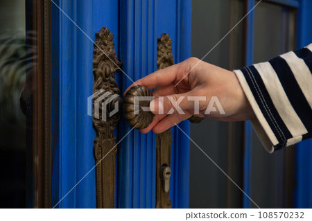 Vintage blue door handle and female hand outdoors, close up 108570232