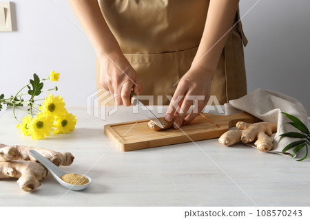 Cutting fresh ginger root on a cutting board Cutting fresh ginger root on a cutting board 108570243