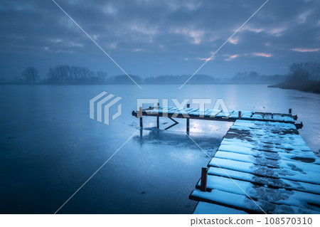 Pier on a frozen lake on a foggy day Pier on a frozen lake on a foggy day 108570310