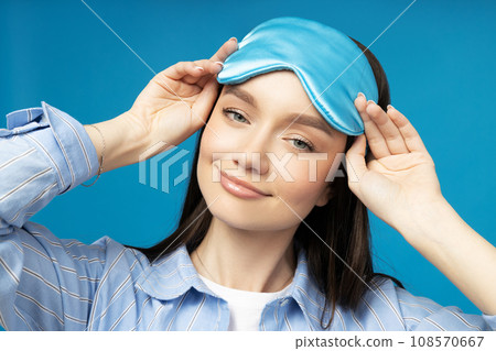 Young woman in a sleeping mask on a blue background 108570667